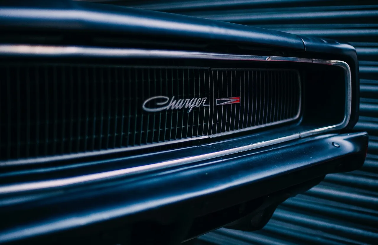 Used Dodge Charger parked on a suburban street at golden hour with a commuter-style sedan in front and a performance trim beh