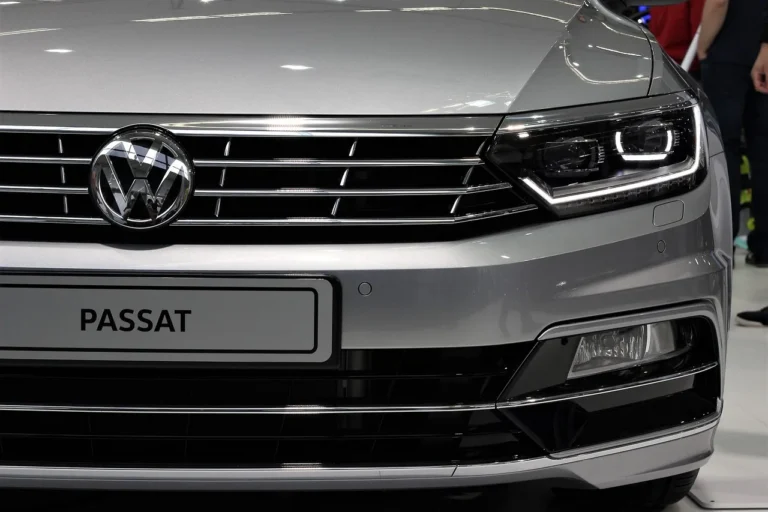 Used VW Passat on a dealership lot with a buyer and mechanic inspecting it