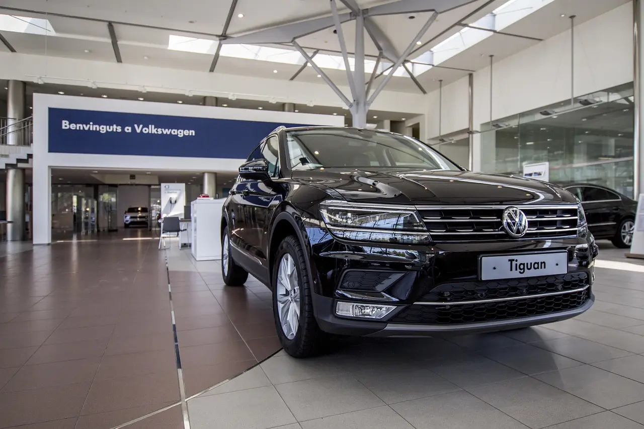 Used VW Tiguan in a dealership lot with a buyer and mechanic discussing it