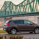 A mechanic inspects a used Ford Escape with the hood open in a dealership lot