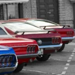 Used Dodge Charger trims lined up on a dealership lot with a shopper comparing them